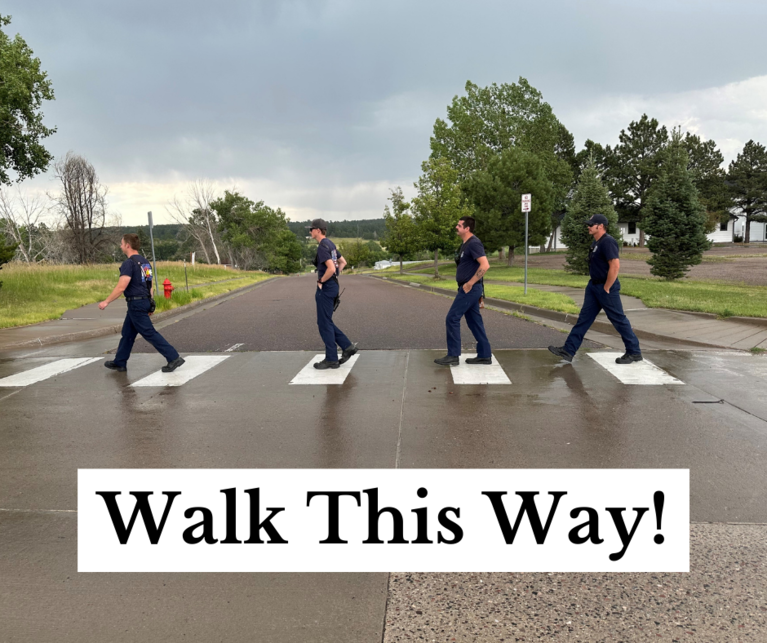 Firefighters crossing the street using a crosswalk with the caption "Walk This Way!"