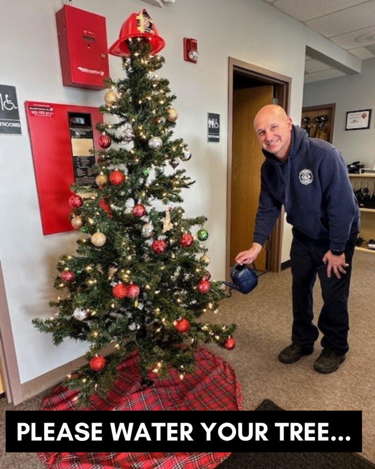 A firefighter watering a Christmas tree with the caption "Please Water Your Tree..."