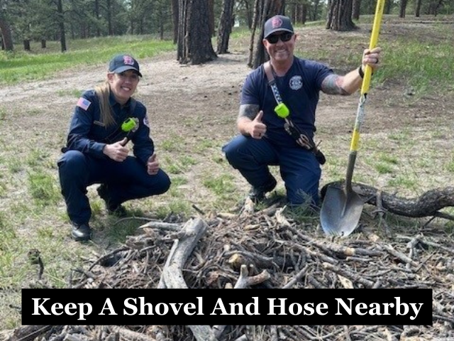 Firefighters kneeling before a burn pile and holding a shovel with the caption "Keep A Shovel And Hose Nearby"