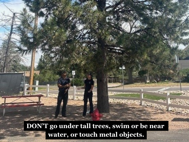 Firefighters standing under a tree with the caption "DON'T go under tall trees, swim or be near water, or touch metal objects."