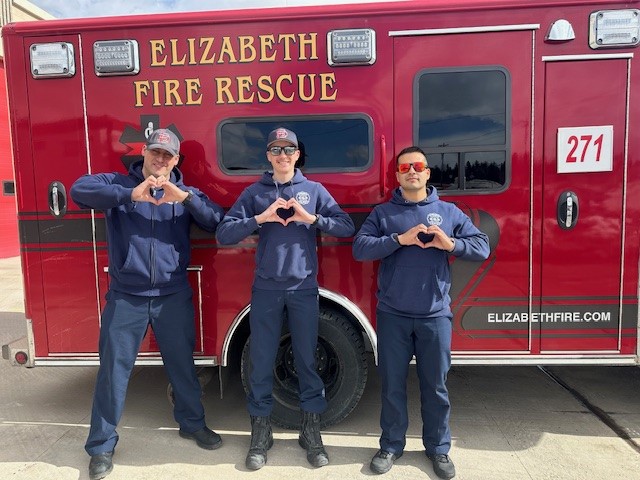 Various fire department activities throughout the year - firefighters standing in front of ambulance posing for a safety message