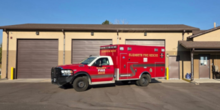 A medic ambulance parked in front of a fire station