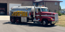 A water tender vehicle parked outside of a fire station