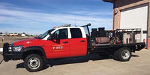 A brush truck parked outside of a fire station