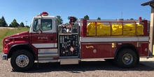 A water tender vehicle parked outside of a fire station