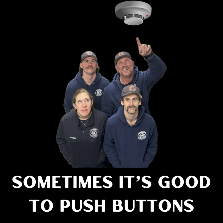Firefighters pointing and looking at a smoke alarm with the caption "Sometimes It's Good to Push Buttons"