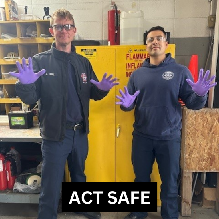 Two firefighters holding up their hands wearing safety gloves with the caption "Act Safe."